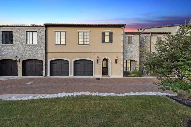 mediterranean / spanish house featuring a garage and a lawn