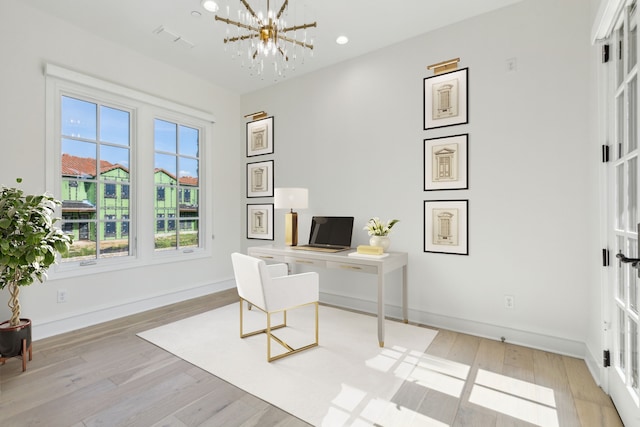 office space featuring an inviting chandelier and light hardwood / wood-style floors