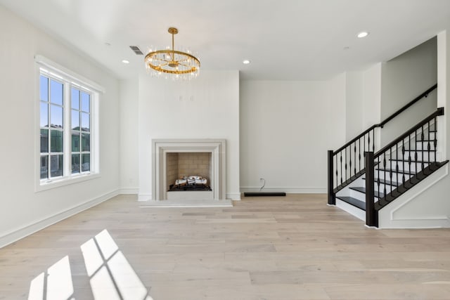 unfurnished living room featuring a notable chandelier and light wood-type flooring