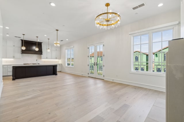 unfurnished living room with sink, light hardwood / wood-style floors, and a chandelier