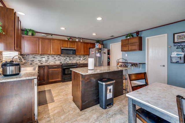 kitchen with sink, a breakfast bar area, stainless steel appliances, a center island, and light stone counters