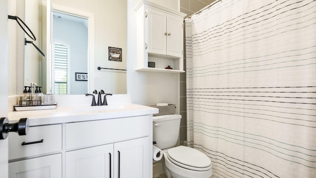 bathroom with walk in shower, vanity, and toilet