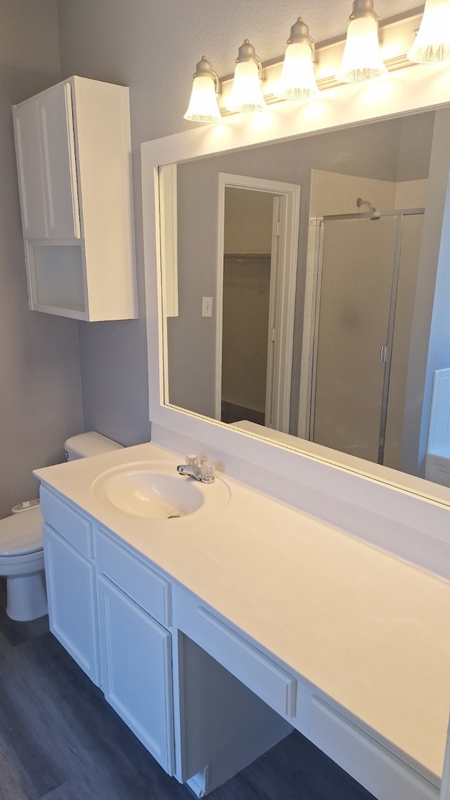 bathroom with hardwood / wood-style flooring, vanity, toilet, and an enclosed shower