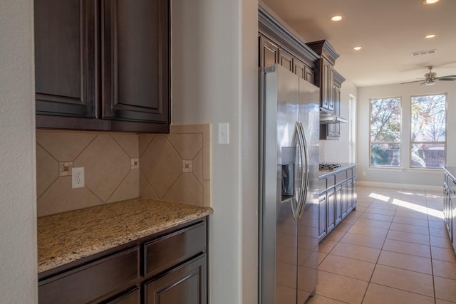 kitchen featuring decorative backsplash, stainless steel appliances, dark brown cabinets, and light tile patterned floors