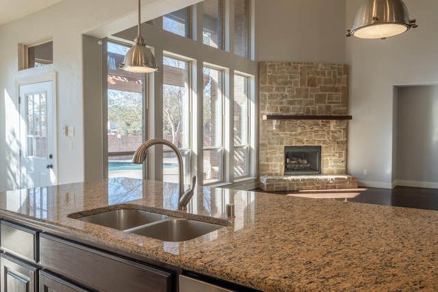 kitchen with light stone counters, sink, hanging light fixtures, and a healthy amount of sunlight