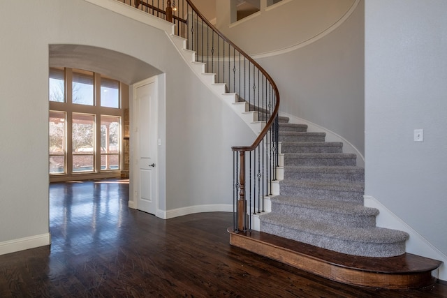 stairs with wood-type flooring and a high ceiling