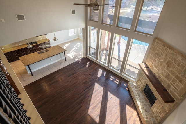 tiled living room featuring sink, a brick fireplace, ceiling fan, and a high ceiling