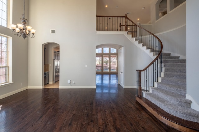 interior space featuring a notable chandelier, a towering ceiling, and dark hardwood / wood-style floors