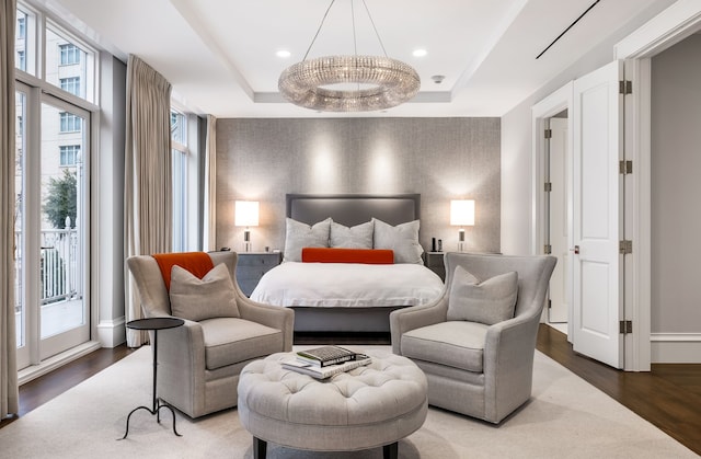 bedroom with dark wood-type flooring, a raised ceiling, and access to outside