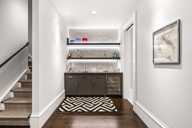 bar with dark hardwood / wood-style flooring, dark brown cabinets, and beverage cooler