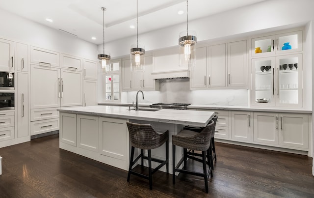 kitchen with a kitchen island with sink, sink, and white cabinets