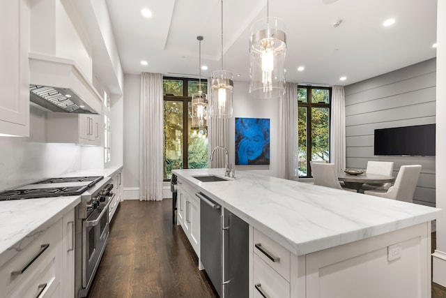 kitchen featuring sink, a large island with sink, pendant lighting, stainless steel appliances, and white cabinets