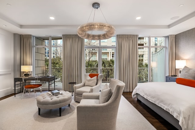 bedroom with a tray ceiling, a wall of windows, and dark hardwood / wood-style floors