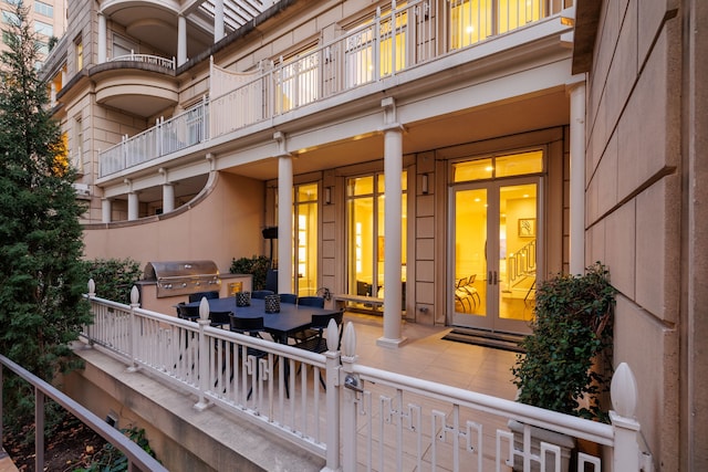 view of exterior entry featuring a patio, a balcony, and french doors