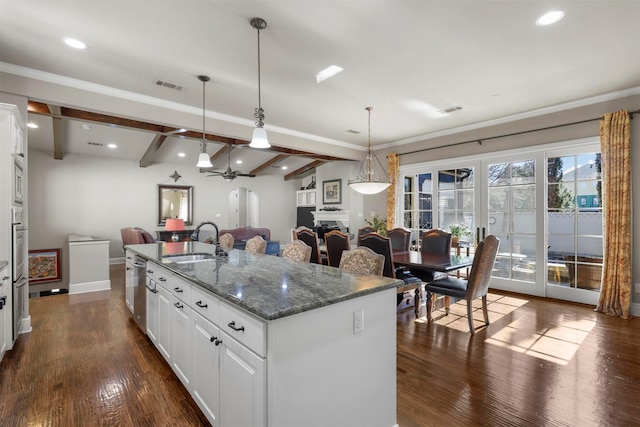 kitchen featuring pendant lighting, beamed ceiling, an island with sink, white cabinetry, and sink