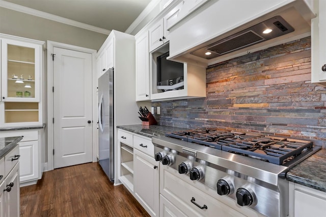 kitchen with appliances with stainless steel finishes, white cabinetry, ornamental molding, decorative backsplash, and custom exhaust hood