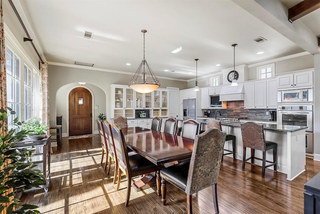 dining space with sink, crown molding, dark wood-type flooring, and beamed ceiling