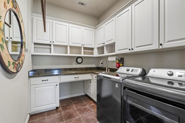 clothes washing area featuring sink, washing machine and dryer, cabinets, and dark tile patterned flooring