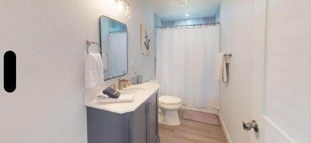 bathroom with a shower with curtain, vanity, toilet, and hardwood / wood-style flooring