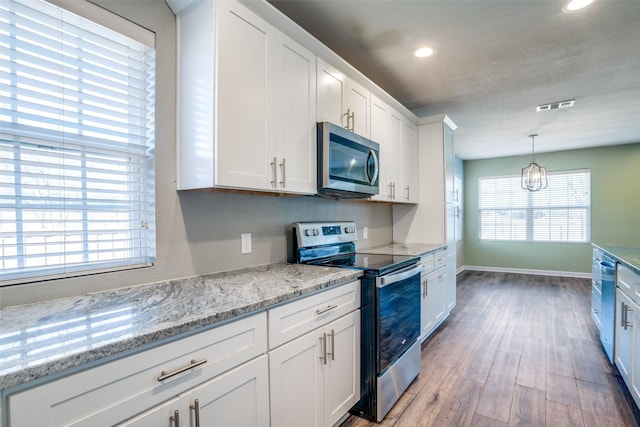 kitchen with pendant lighting, stainless steel appliances, hardwood / wood-style flooring, and white cabinets