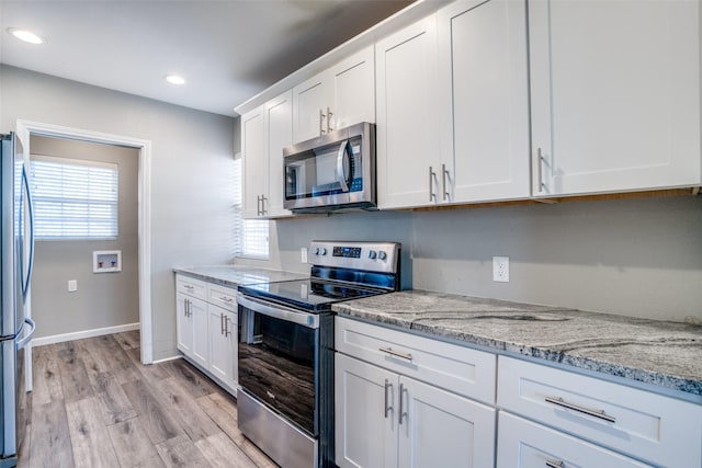 kitchen with light stone counters, stainless steel appliances, light wood-type flooring, and white cabinets