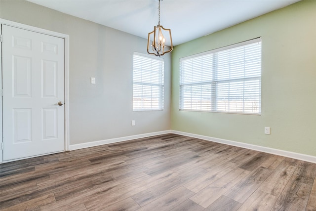 unfurnished room featuring a notable chandelier and wood-type flooring