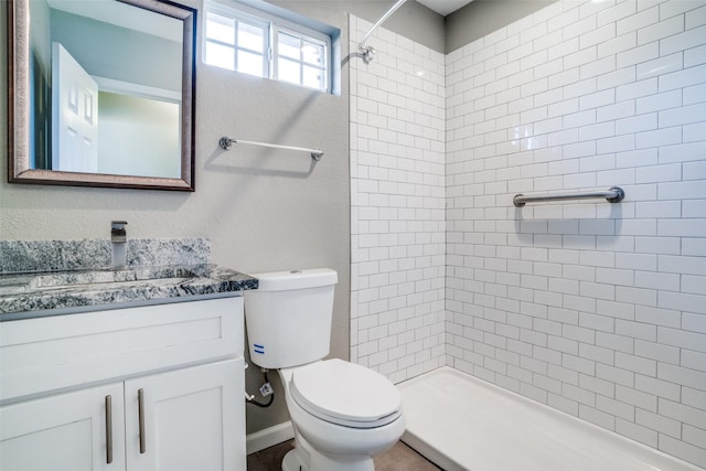 bathroom with vanity, toilet, and a tile shower