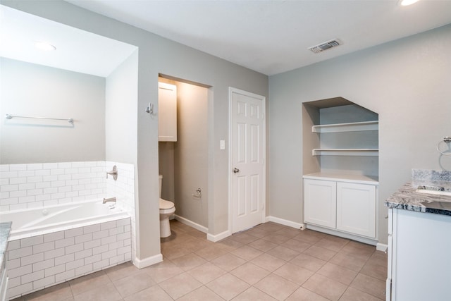 bathroom featuring vanity, tile patterned floors, tiled bath, and toilet