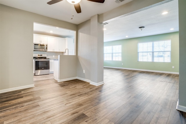 unfurnished living room with sink, light hardwood / wood-style flooring, and ceiling fan