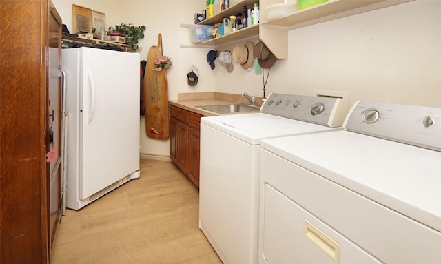 laundry area featuring cabinets, separate washer and dryer, sink, and light hardwood / wood-style floors