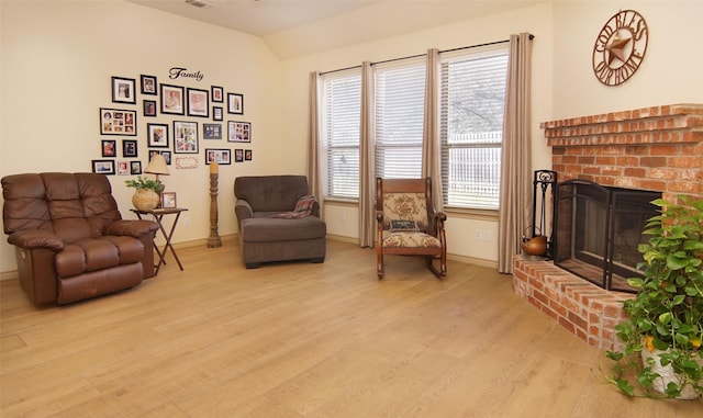 sitting room with lofted ceiling, plenty of natural light, a fireplace, and light wood-type flooring