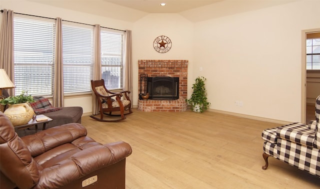 living room with a fireplace, light hardwood / wood-style floors, and vaulted ceiling