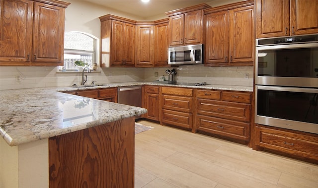 kitchen with stainless steel appliances, sink, light stone counters, and kitchen peninsula