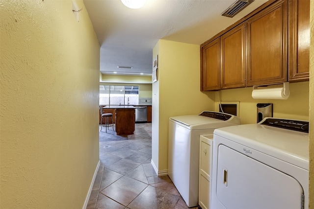 laundry area with cabinets, light tile patterned floors, and washing machine and clothes dryer