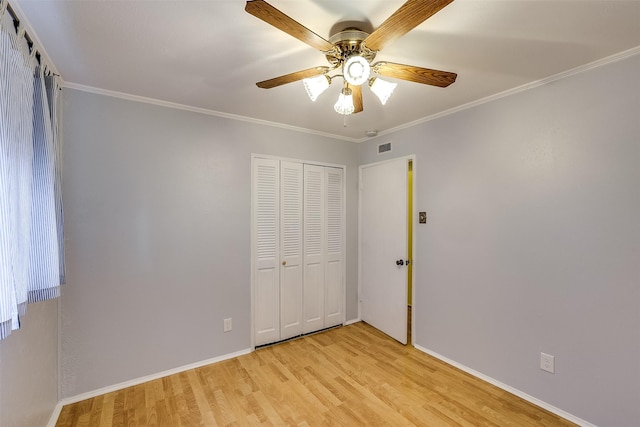 unfurnished bedroom with ceiling fan, ornamental molding, a closet, and light wood-type flooring