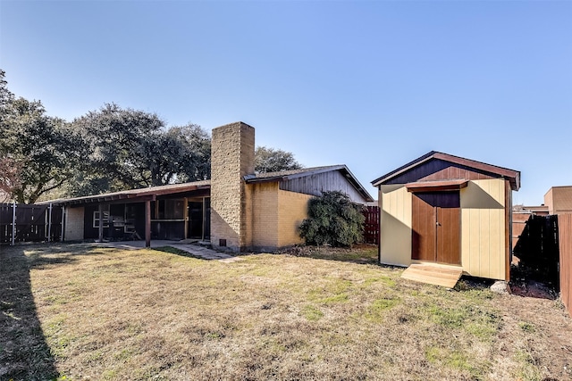 rear view of property featuring a yard and a storage unit