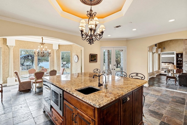 kitchen featuring stainless steel microwave, sink, hanging light fixtures, a notable chandelier, and a healthy amount of sunlight