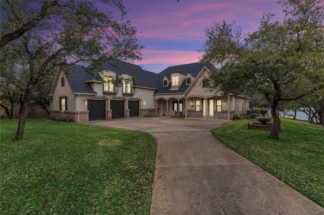 french provincial home featuring a garage and a lawn