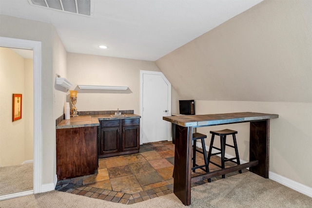 interior space with dark brown cabinets, sink, lofted ceiling, and dark carpet