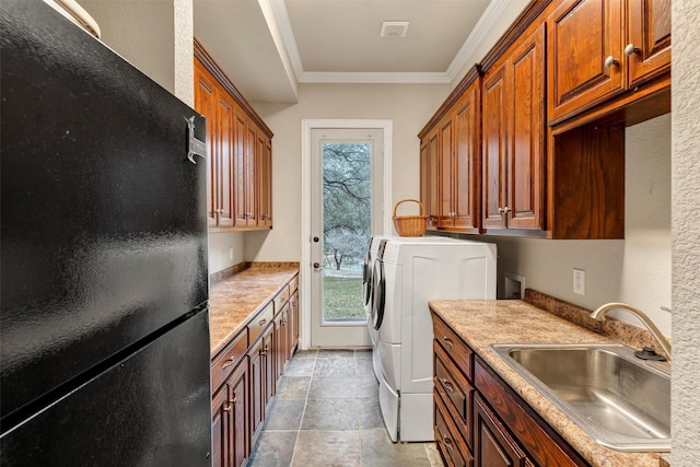 washroom featuring sink, ornamental molding, cabinets, and washing machine and dryer