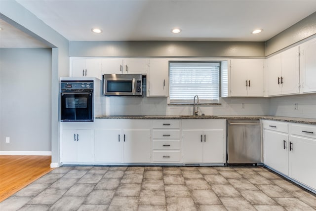 kitchen with sink, dark stone countertops, white cabinets, decorative backsplash, and stainless steel appliances