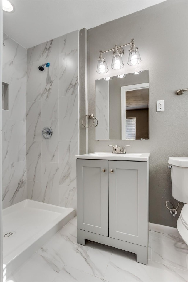 bathroom with vanity, toilet, and tiled shower