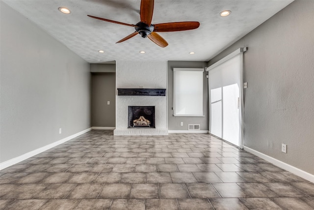 unfurnished living room featuring a brick fireplace and ceiling fan