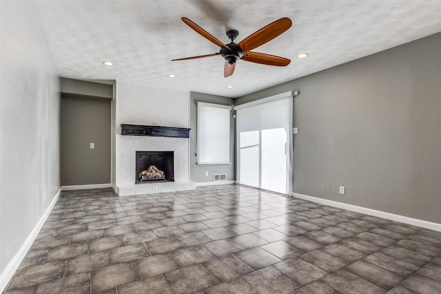 unfurnished living room with ceiling fan, a textured ceiling, and a fireplace