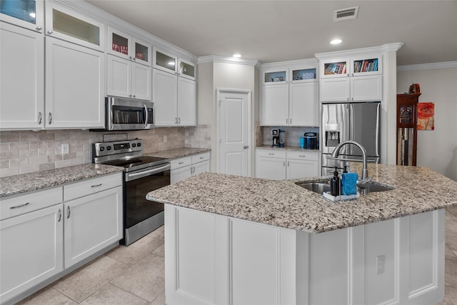 kitchen with an island with sink, stainless steel appliances, sink, and backsplash