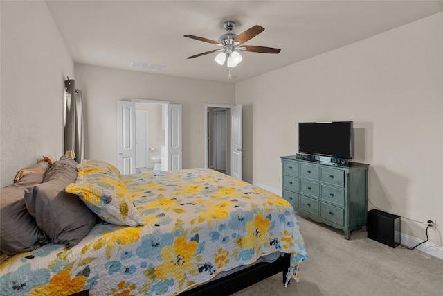 bedroom with ceiling fan, light colored carpet, and ensuite bath