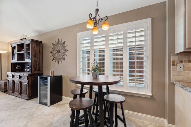 dining space featuring light tile patterned floors, beverage cooler, and a chandelier