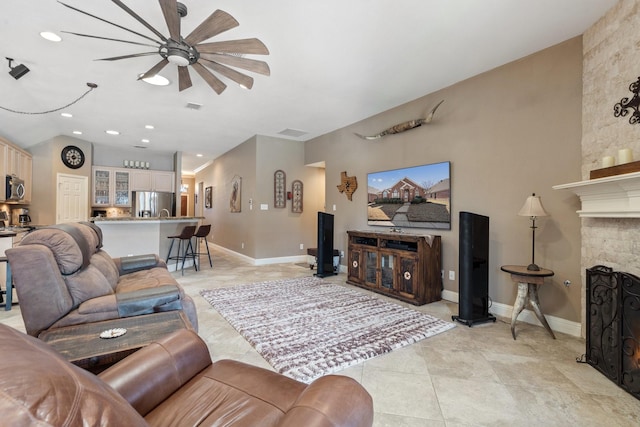 tiled living room with ceiling fan and a fireplace