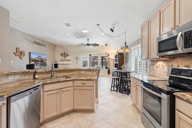 kitchen featuring lofted ceiling, light brown cabinetry, sink, tasteful backsplash, and stainless steel appliances