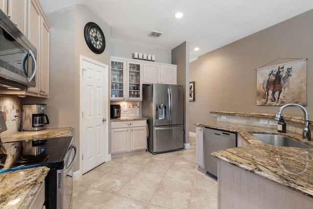 kitchen with light stone counters, appliances with stainless steel finishes, sink, and decorative backsplash